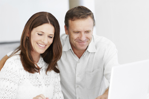 A man and woman looking at a computer screen.